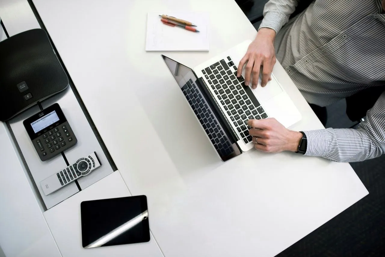 Vista cenital de una mesa de trabajo con portátil, calculadora y teléfono