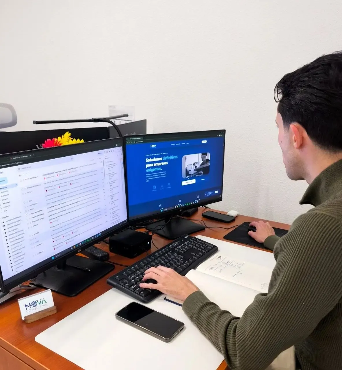 Profesional trabajando con dos monitores y un teclado en su escritorio